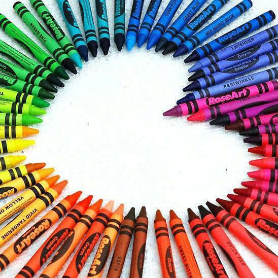 A collection of crayons arranged in a semi-circle, with each color meticulously organized and placed side-by-side.